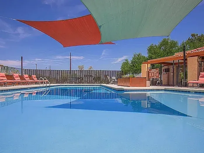Swimming pool at Puesta del Sol property in Tucson, Arizona, surrounded by desert landscaping and sunny Southwestern scenery.