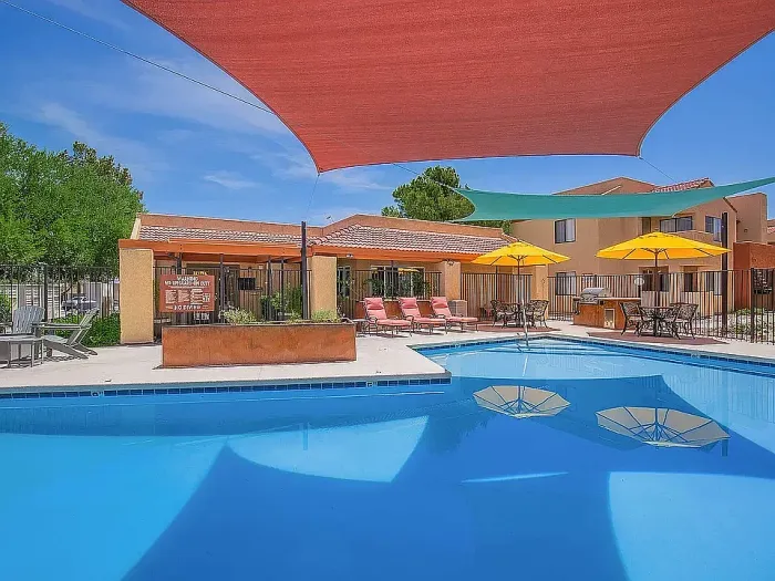 Resort-style swimming pool at Puesta del Sol in Tucson, Arizona, surrounded by landscaped grounds.