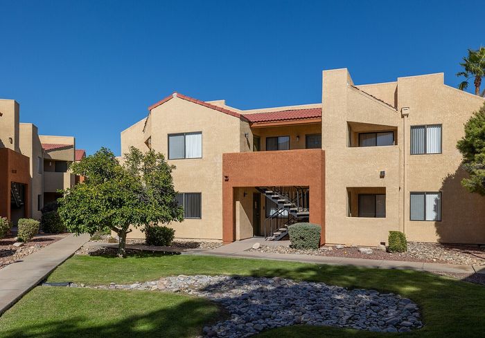 Sunlit apartment complex with Mediterranean-style architecture, featuring inviting green lawns and modern amenities.