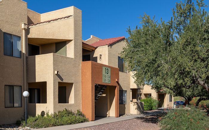 Charming apartment building with rustic architecture, lush greenery, and a sunlit exterior, offering tranquil living spaces.