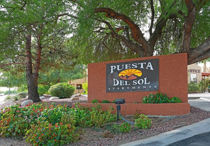 Welcoming entrance of Puesta Del Sol Apartments surrounded by lush greenery and vibrant flowers.
