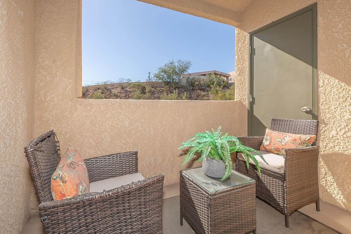 Charming outdoor patio featuring cozy wicker seating, vibrant cushions, and a lush potted plant, offering serene views of the landscape.