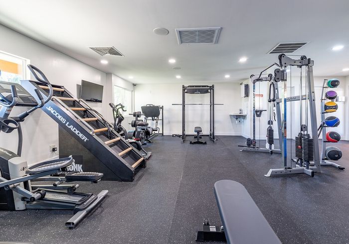 Modern fitness center with diverse exercise equipment, ample natural light, and a sleek design for an invigorating workout experience.