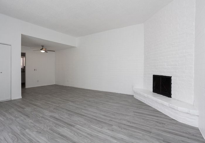 Bright and spacious living room with sleek laminate flooring and a charming white brick fireplace, offering a modern and cozy ambiance.