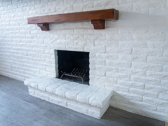 Charming living room with a rustic white brick fireplace and modern grey flooring, perfect for cozy evenings.