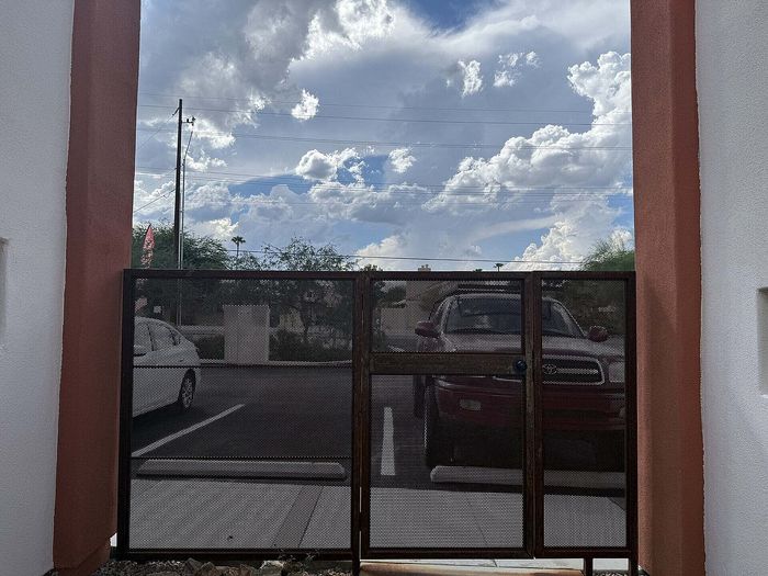 Inviting apartment entrance with modern gate design under a picturesque cloudy sky, offering secure and stylish access.