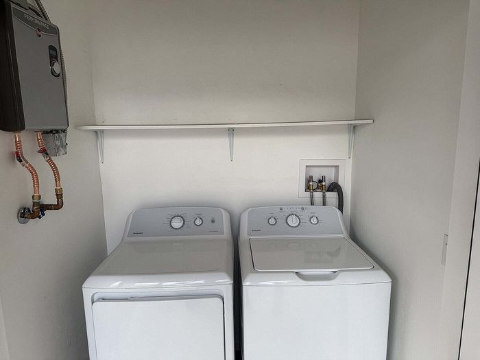 Contemporary laundry area featuring a sleek washer and dryer with modern shelving above for convenient storage solutions.