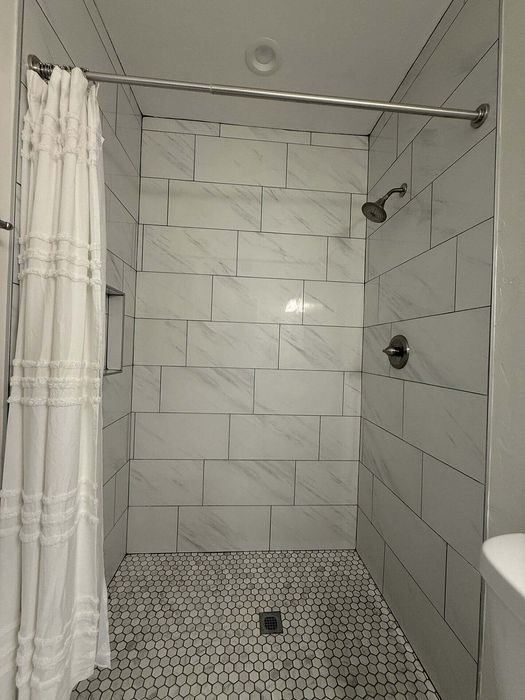 Elegant bathroom showcasing a modern walk-in shower with luxurious marble tiles and a chic shower curtain, offering a spa-like experience.