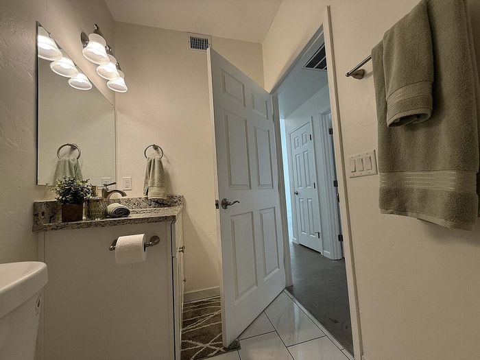 Inviting bathroom with granite countertops, warm lighting, and elegant fixtures, offering a cozy and sophisticated ambiance.