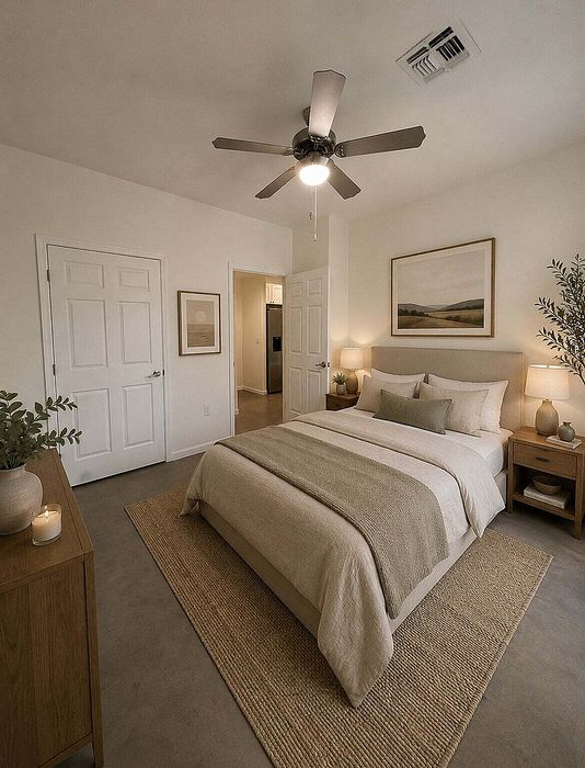 Inviting bedroom featuring a cozy bed with soft linens, elegant decor, and a soothing ambiance enhanced by warm lighting and a ceiling fan.