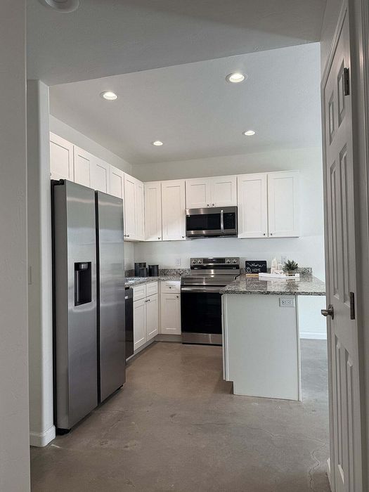 Modern kitchen with sleek stainless steel appliances, white cabinetry, and elegant granite countertops.