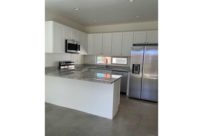 Modern kitchen with sleek stainless steel appliances, elegant granite countertops, and pristine white cabinetry in a stylish apartment.