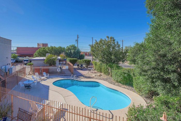 Inviting outdoor pool area with lounge chairs, surrounded by lush greenery and clear blue skies, perfect for relaxation and leisure.