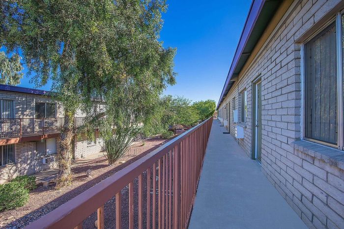 Charming apartment exterior with modern brickwork, lush greenery, and a sunlit walkway, perfect for tranquil living.