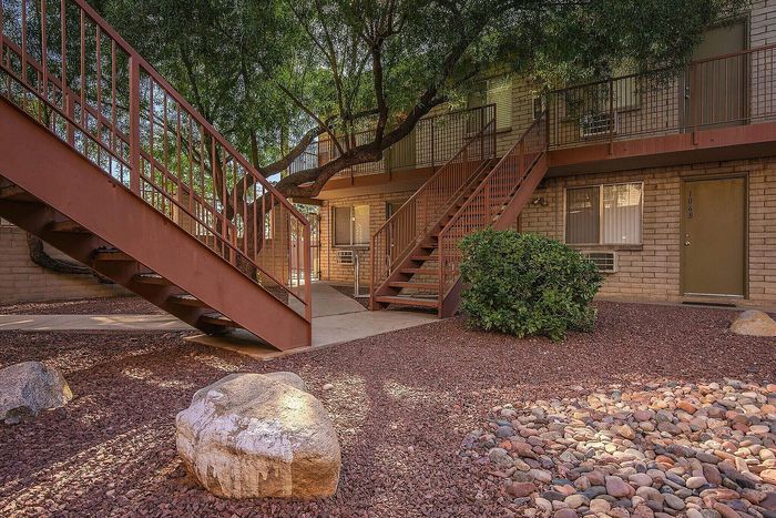 Charming apartment exterior with rustic staircases and lush greenery, offering a warm and inviting atmosphere.