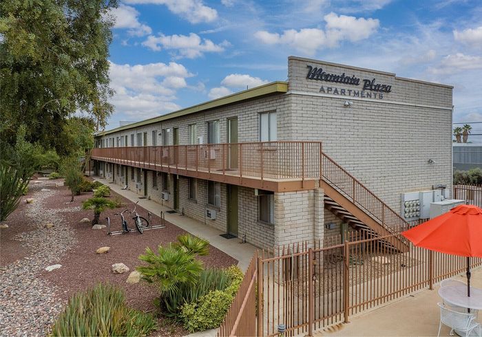 Charming Mountain Plaza Apartments exterior showcasing a modern facade with lush landscaping, set against a bright, clear sky.