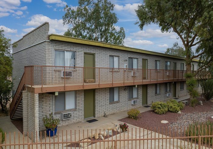 Charming two-story apartment building with brick exterior and lush landscaping, offering a welcoming and serene environment.