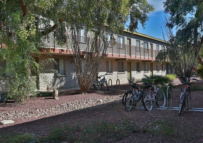Charming apartment exterior with lush greenery, convenient bike racks, and a tranquil setting.