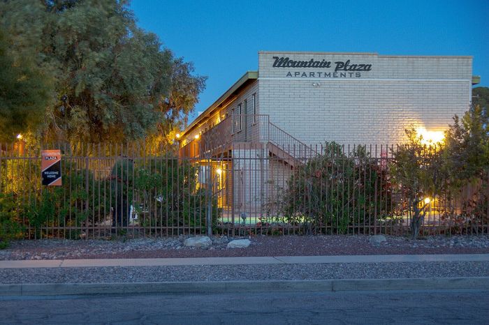 Charming Mountain Plaza Apartments exterior at dusk, showcasing inviting lights and lush greenery.