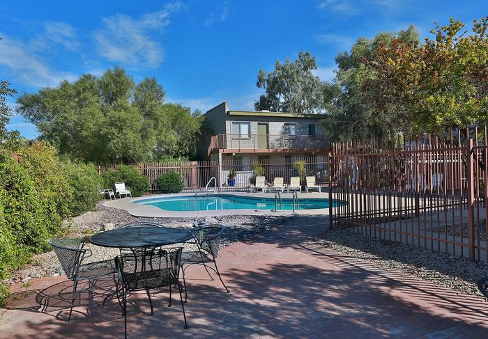 Idyllic apartment complex with inviting swimming pool, surrounded by lush greenery and comfortable lounge chairs for relaxation.