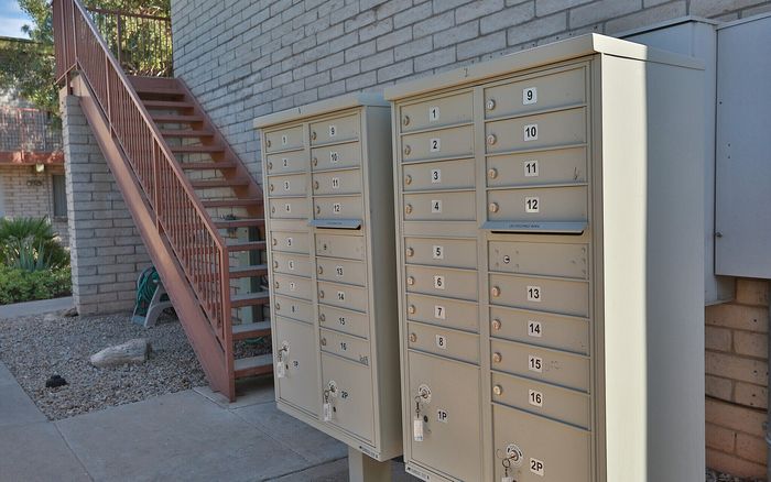 Charming outdoor mailboxes beside a brick wall with a rustic staircase, surrounded by serene greenery.