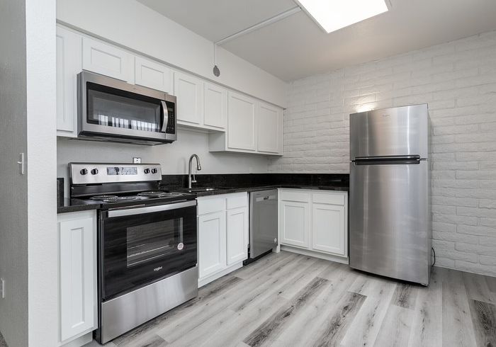 Modern kitchen with sleek stainless steel appliances, elegant white cabinetry, and stylish gray flooring.