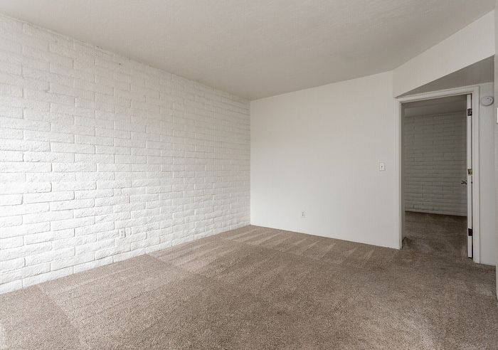 Inviting room with fresh white brick accent wall and plush carpet, offering a cozy and modern atmosphere.