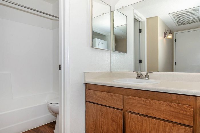 Bright and modern bathroom with elegant wood cabinetry, sleek countertops, and a stylish mirror, offering a serene and contemporary feel.