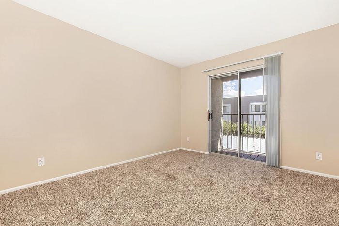 Bright and inviting bedroom featuring plush carpet and access to a private balcony.