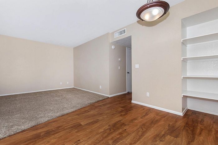 Bright living space with elegant hardwood flooring and built-in shelving, perfect for a cozy and versatile interior design.