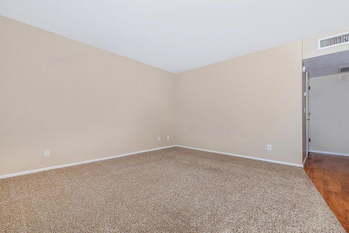 Spacious empty room with soft beige carpet and fresh paint, perfect for personalizing your dream space.
