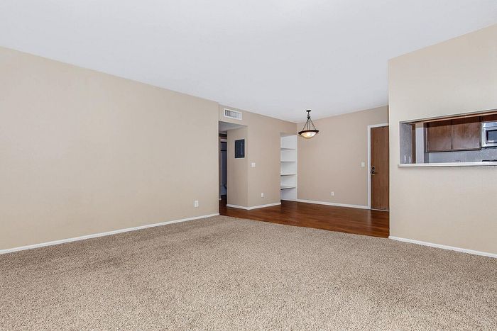 Sophisticated apartment living room showcasing plush carpeting, warm-toned hardwood floors, and a stylish light fixture for modern comfort.