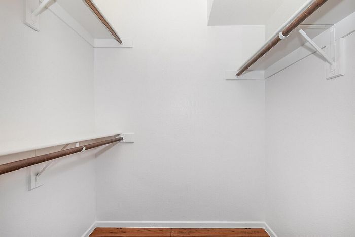 Spacious walk-in closet with sleek wooden floors and ample hanging space.
