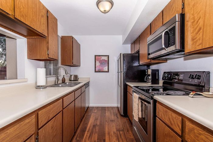 Modern kitchen with sleek stainless steel appliances, elegant wood cabinetry, and warm hardwood flooring.