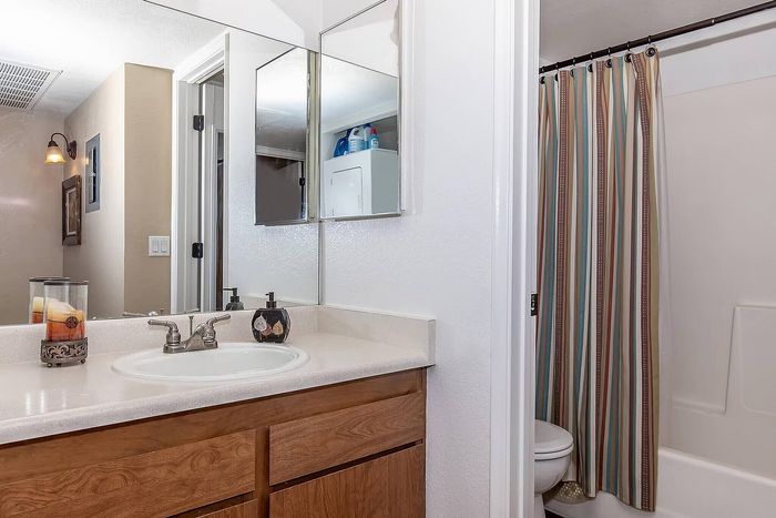 Inviting bathroom with elegant wooden cabinetry, stylish fixtures, and a colorful striped shower curtain.