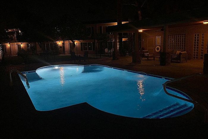 Inviting night view of a serene, illuminated swimming pool surrounded by cozy seating in a tranquil outdoor setting.