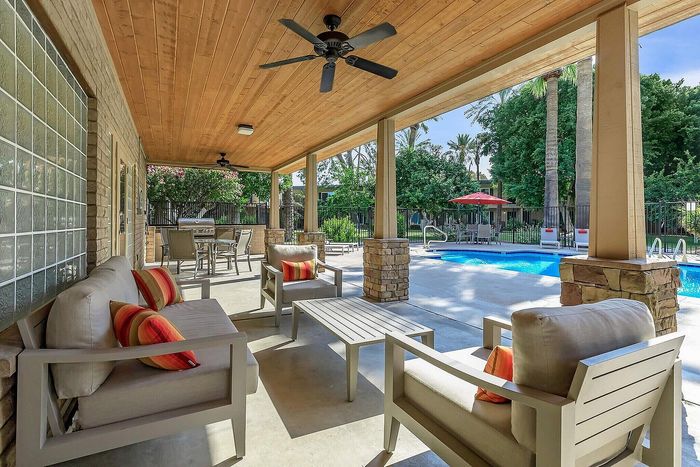 Charming outdoor patio with cozy seating overlooking a pristine pool and lush greenery, ideal for relaxation and entertaining.