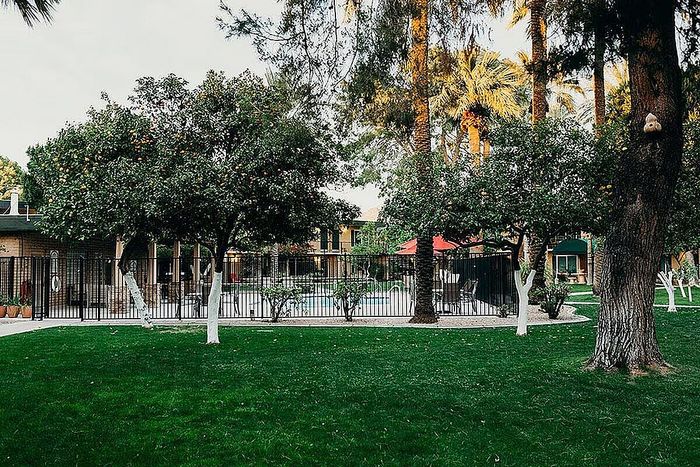 Charming apartment complex with lush greenery, a sparkling pool, and inviting outdoor seating, perfect for relaxation.