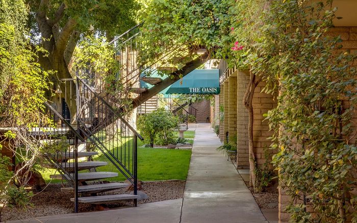 Charming garden path at The Oasis, featuring lush greenery and elegant iron stairs.