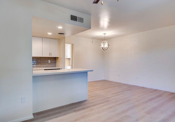Bright and inviting open-plan living area with stylish wood flooring and a modern kitchen featuring sleek cabinetry and chic lighting.