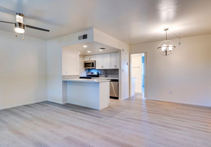 Modern open-concept apartment with sleek kitchen, stylish light fixtures, and elegant wood flooring.