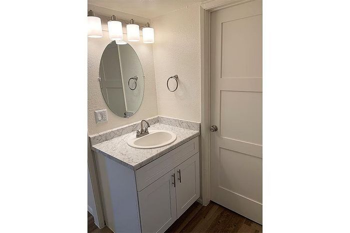 Elegant bathroom featuring a modern vanity with marble countertop, oval mirror, and sleek lighting fixtures.