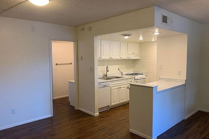 Inviting apartment kitchen with stylish white cabinetry, modern appliances, and warm wood flooring, perfect for culinary creativity.
