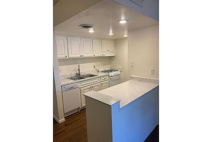 Cozy, modern kitchen with elegant white cabinetry, sleek countertops, and built-in appliances.