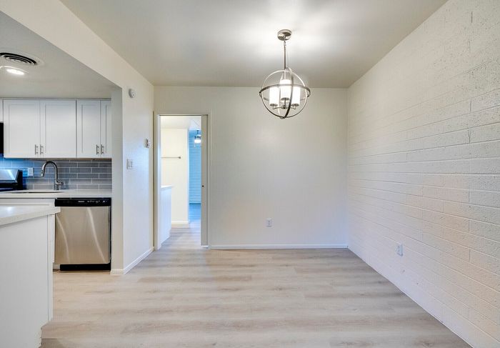 Modern kitchen and dining area with sleek white cabinetry, stainless steel appliances, and elegant lighting, offering a bright and inviting atmosphere.