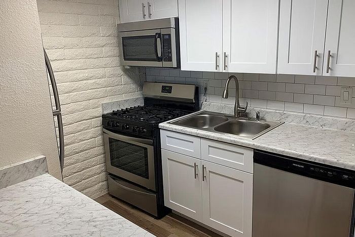 Modern kitchen with sleek stainless steel appliances, white cabinetry, and elegant marble countertops.
