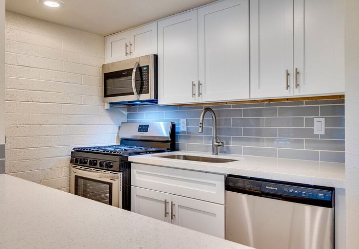 Modern kitchen with sleek stainless steel appliances, elegant white cabinetry, and stylish tile backsplash.
