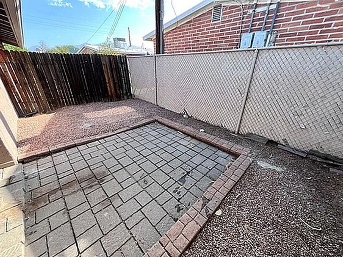 Charming outdoor patio area with a paved stone surface and privacy fencing, perfect for relaxation and entertaining.