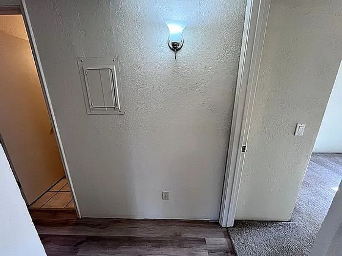 Inviting hallway with elegant sconce lighting and sleek flooring, leading to a cozy carpeted room.