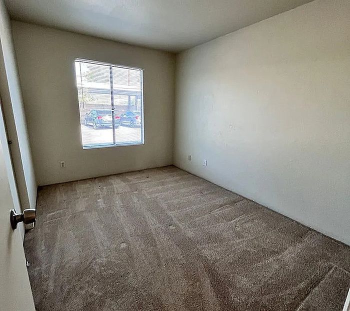 Bright and inviting bedroom with fresh carpet and a large window for natural light.
